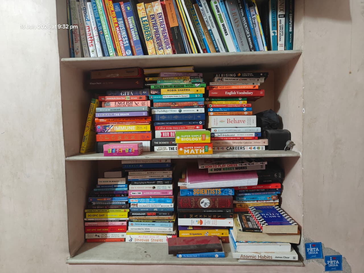 A home bookshelf packed with books, spines facing out, stacked and shelved across several rows